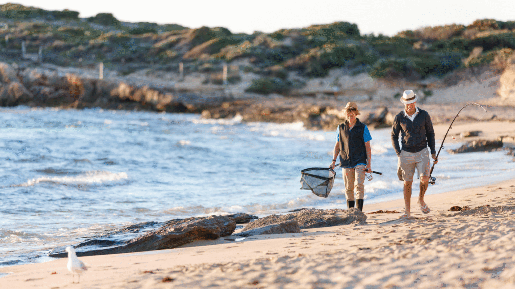 Grandsonand Grandfather walking with fishing rods across beach